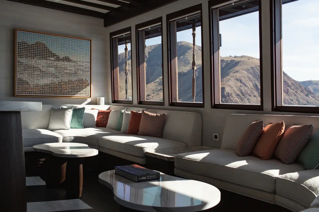 Vela’s indoor lounge with cream sofas, colourful cushions and large windows overlooking island hills