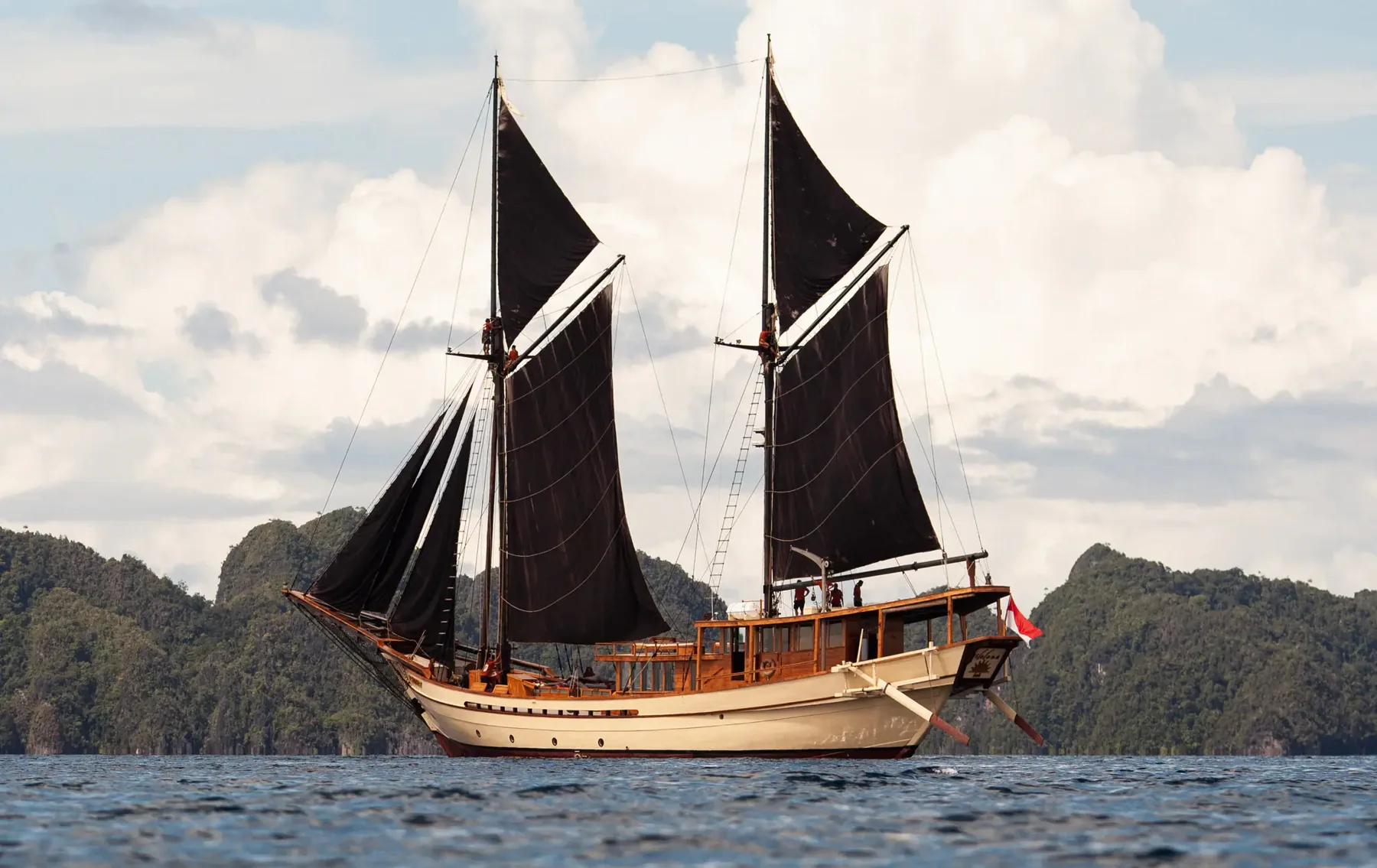 Silolona, a wooden phinisi yacht, sailing with dark sails raised