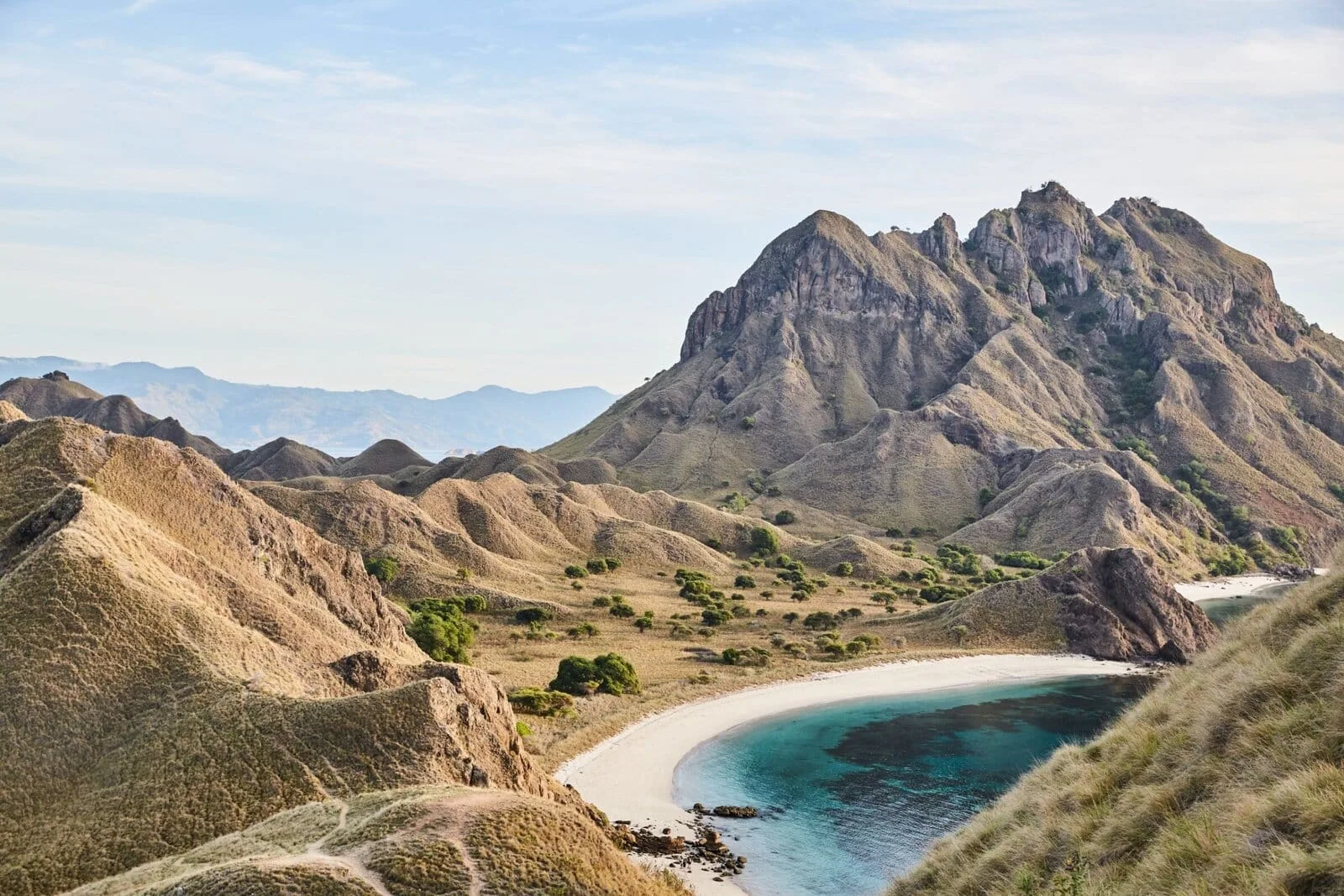 Rugged hills and a curved beach beside turquoise water in the Komodo archipelago