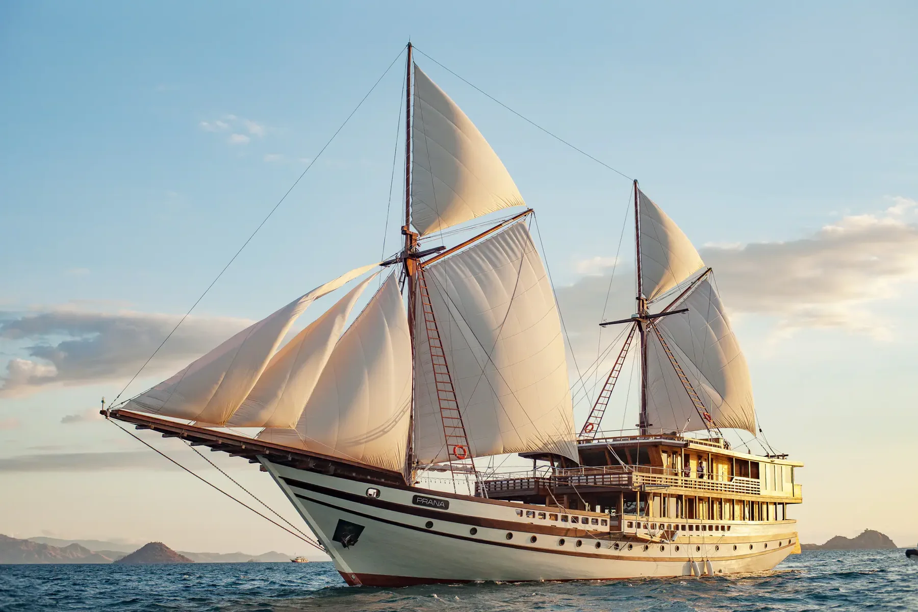 Prana by Atzaró, a wooden phinisi yacht, with cream sails raised on blue water