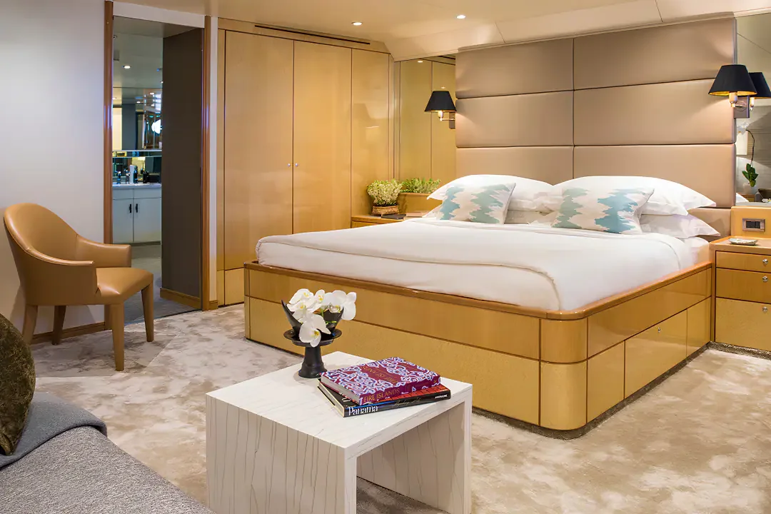 A cabin aboard Aqua Blu with a double bed, seating and a bathroom entrance